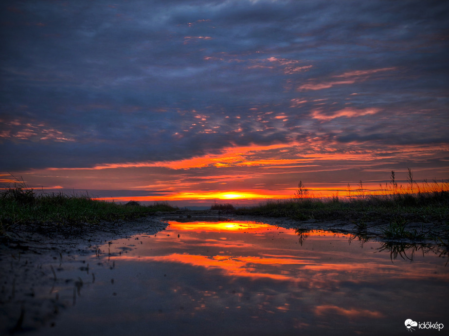 Naplemente színei a bőséges esők mementójáról tükröződve