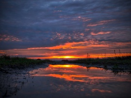 Naplemente színei a bőséges esők mementójáról tükröződve