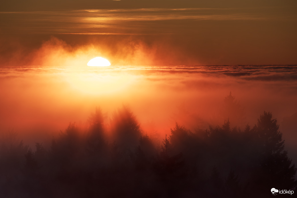 Színpompás, tüzes naplemente a ködtenger határán