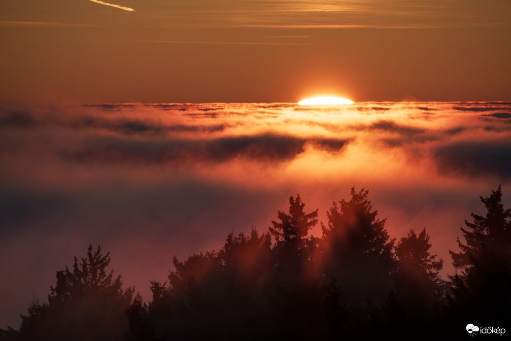 Színpompás, tüzes naplemente a ködtenger határán