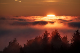 Színpompás, tüzes naplemente a ködtenger határán